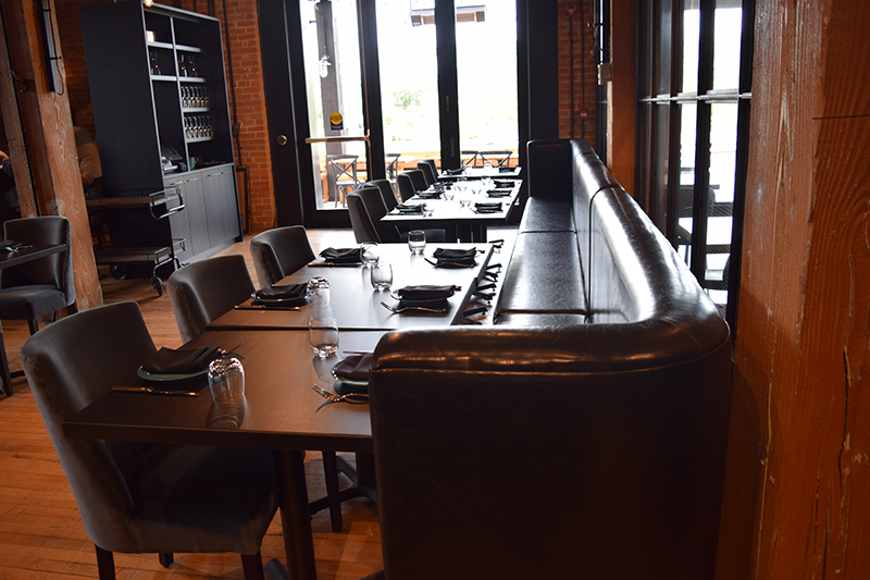 Grey bench seating across from wooden chairs